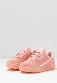 Scarpe da ginnastica color rosa con tomaia in suede, suola in gomma, chiusura con lacci e dettagli ricamati sul linguette e sul lato.