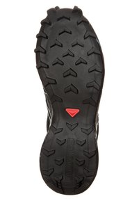 Svart gummiyttersula med djupa multidirektionella mönster och en röd logotyp. Har en strukturerad yta för ökad grepp och stabilitet.