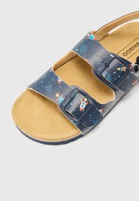 Blå sandaler med romfart-tema print av raketter og planeter, to justerbare stropper og en beige teksturert kork såle.