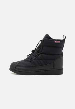 Baskets montantes noires avec dessus rembourré, embout en caoutchouc arrondi, laçage à l'avant et languette au talon, vues de profil sur un fond uni.