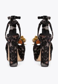 Czarne sandały na wysokim obcasie z wykończeniem w leoparda, otwarty z tyłu, z złotymi akcentami i paskami na kostkę w stylu owinięcia.