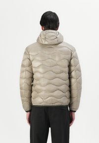 Padded jacket in metallic taupe, featuring a scalloped quilted design, hood, and elastic cuffs with a contrasting green trim.