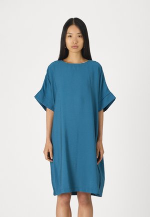 Robe ample de couleur sarcelle avec des manches courtes, un col rond et des fentes sur les côtés. Fabrication en tissu léger avec une texture lisse.