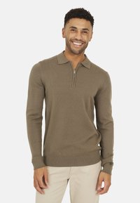 Pullover marrone a maniche lunghe con colletto a mezza zip. Realizzato in un morbido materiale a maglia con polsini e orlo a coste. Design semplice e monocromatico.