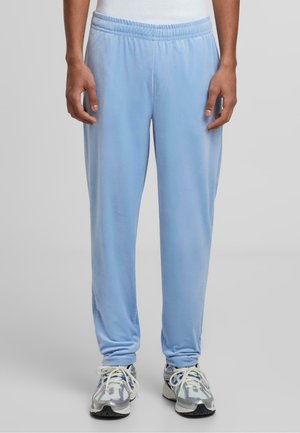 Lys blå joggebukser laget av mykt stoff, med elastisk midjebånd og tilsmalnede ben, paired med grå joggesko.