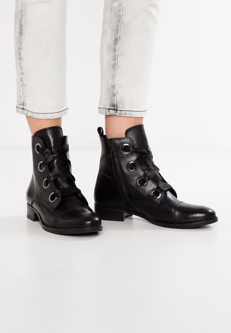 Bottines en cuir noir avec bouts arrondis, lacets sur le devant, œillets argentés et fermeture éclair latérale. Talon carré bas et texture lisse.