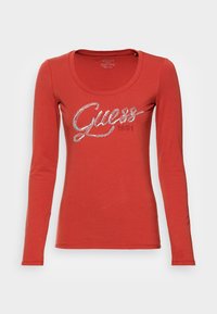 Rode langärmige t-shirt met een ronde halslijn, voorzien van een zilver glinsterend "Guess 1981" logo over de borst. Zachte, elastische katoenstof.