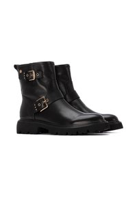 Botas de cuero negro hasta el tobillo con una suela gruesa, que cuentan con dos correas con hebillas doradas y un acabado suave. Diseño duradero y resistente.