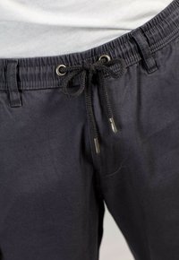 Pantalones cortos azul marino hechos de una tela ligera con cintura elástica, cierre de cordón y ojales de metal. Textura suave y diseño sencillo.