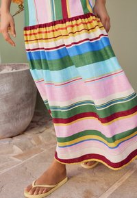 Maxi dress featuring multicolored horizontal stripes in pink, green, yellow, and blue with a gathered waistline and lightweight fabric texture.