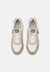 Baskets beiges et blanches avec une tige en mesh, des accents en daim, des lacets plats et un zip latéral. Semelle en caoutchouc et col rembourré.