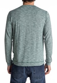 Camicia a maniche lunghe grigio melange con colletto rotondo, realizzata in tessuto strutturato. Presenta un orlo dritto e polsini a costine. Dettagli di cucitura a vista.