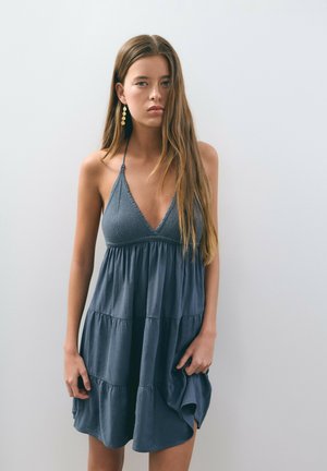 Vestido de verano azul en capas con un profundo escote en V, hecho de tela suave. Presenta tirantes finos y un corsé texturizado, con una silueta fluida.
