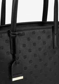 Sac fourre-tout en cuir noir avec un motif floral en relief, texture lisse, doubles anses et une étiquette en métal doré.