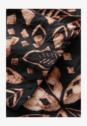 Sort stof med komplekse, organiske former i brune nuancer, med en struktureret overflade og synlige sømdetaljer.