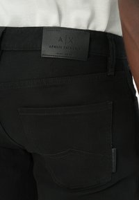 Jeans negre din denim, cu un buzunar posterior ce prezintă un design subtil de cusătură și o etichetă din piele neagră cu marcaj la talie.