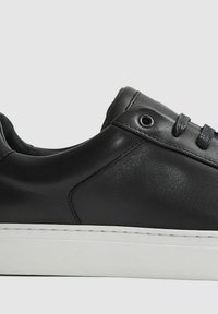 Sneaker in pelle nera con finitura liscia, punta rotonda, suola in gomma bianca e lacci neri con occhielli in metallo.