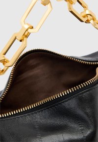 Svart läderhandväska med handtag i guldkedja, dragkedjestängning och brunt tygfoder. Texturerad yta med synliga sömdetaljer.