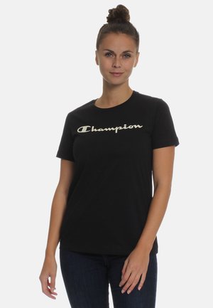 Czarna bawełniana koszulka z krótkim rękawem, z wyraźnym kremowym logo "Champion" na piersi. Prosty design i krój.