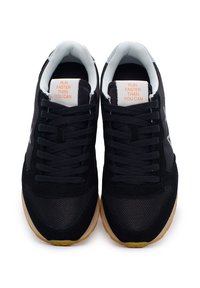 Scarpe sportive nere con tomaia in rete traspirante, suola in gomma, testo arancione sulla linguetta e design stratificato per maggiore texture e supporto.