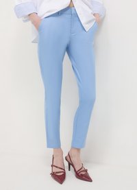 Hellblaue, maßgeschneiderte Hose mit engem Schnitt. Das Material wirkt glatt mit leichtem Glanz. Kombiniert mit burgunderroten High Heels.