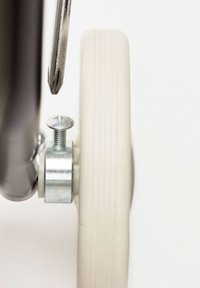 Hvid gummihjul med en rillede overflade, fastgjort til en metallaksel med en sølvfarvet skrue. En skruetrækker ligger tæt på skruen.