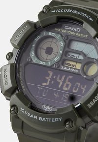 Montre numérique Casio avec un boîtier en résine vert foncé, étanche jusqu'à 100 mètres, dotée d'un affichage LCD, de réveils et de fonctions de matériel de pêche.