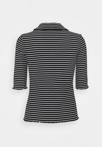 Blusa a rayas en blanco y negro con cuello, mangas de tres cuartos y dobladillo en forma de ondas. Fabricada en tela acanalada.