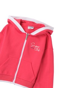 Sudadera rosa con cremallera y acentos blancos, bolsillos tipo canguro y un logo en la parte delantera. Fabricada en tejido suave con puños y dobladillo acanalados.