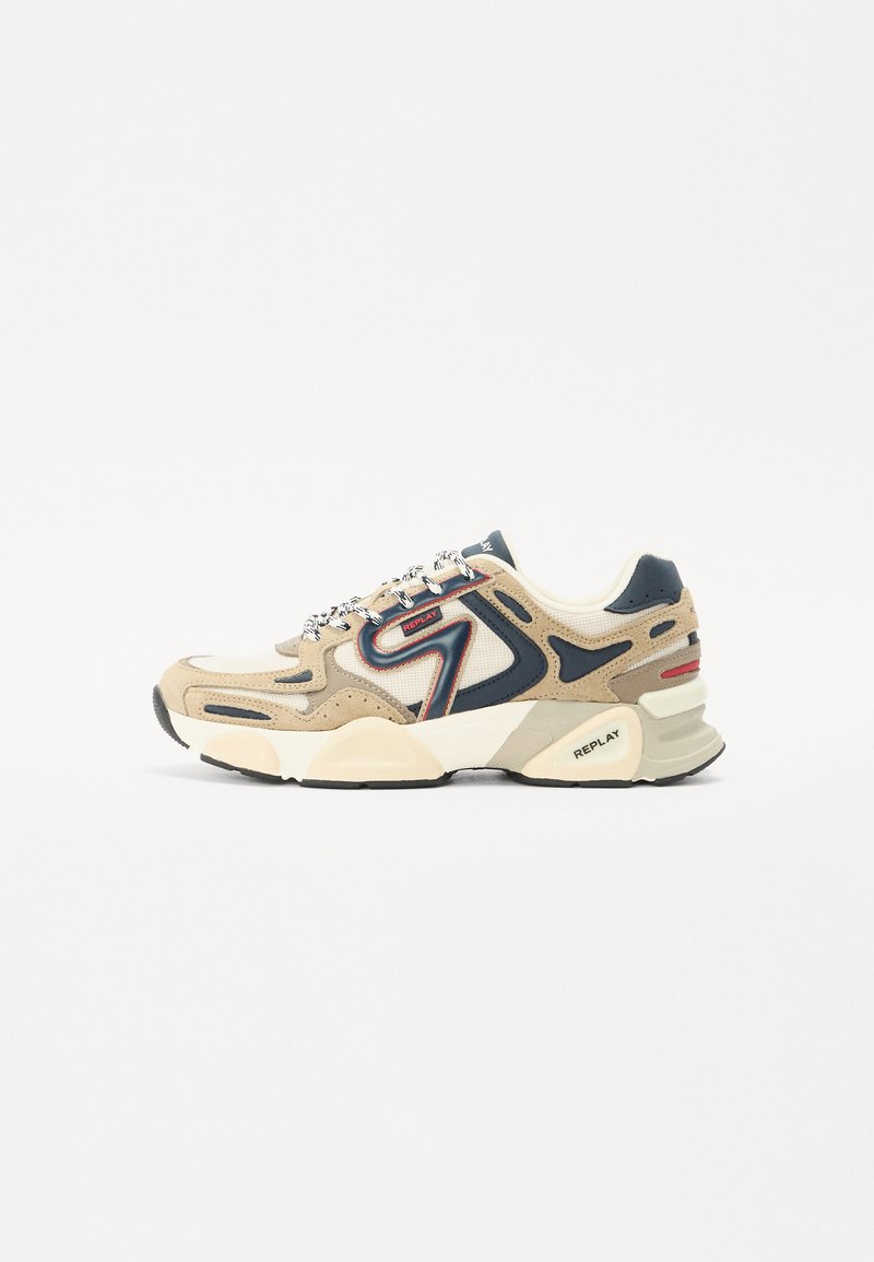 Beige en marineblauwe sport sneaker van mesh en suede materialen, met getextureerde overlays, een witte tussenzool, gedurfde rode accenten en patroonveters.