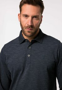 Marineblaues Poloshirt aus strukturiertem Stoff, mit drei Knöpfen am Kragen und einem dezenten bestickten Logo auf der Brust.