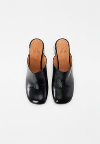 Mule aperte nere in pelle, con superficie liscia, design a punta quadrata e tacco basso. La soletta è color cuoio con un logo del brand impresso.