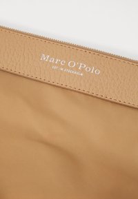 Tan leren pouch met een gestructureerde afwerking en een zilveren rits. Bevat "Marc O'Polo EST. IN STOCKHOLM" in het wit gegraveerd. Zachte binnenvoering.