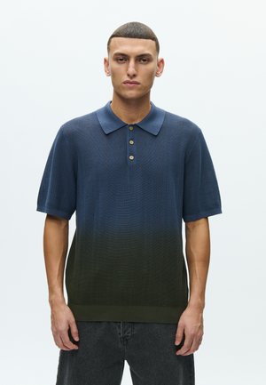 Tricou polo cu mâneci scurte, tricotat texturat, cu un degrade de albastru spre verde. Dispune de un guler și o fâșie cu trei nasturi.