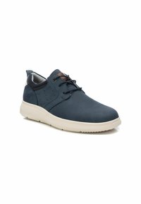 Zapatilla azul marino con parte superior texturizada, suela beige, diseño con cordones y acento marrón contrastante en el lateral y la lengüeta.