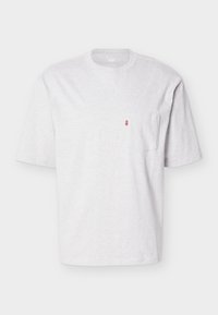 Απλό ανοιχτό γκρι κοντομάνικο μπλουζάκι με στρογγυλή λαιμόκοψη και μικρή τσέπη στο στήθος που έχει κόκκινη ετικέτα στην αριστερή πλευρά.