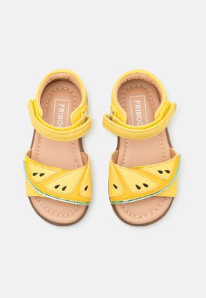 Gelbe Sandalen mit einem Wassermelonen-Scheiben-Design, aus synthetischem Material gefertigt und mit verstellbaren Klettverschlüssen ausgestattet. Braune Innensohlen mit weißer Naht.
