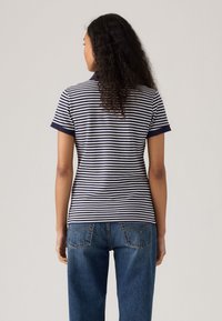 Marinblå och vit randig polo med korta ärmar och en kontrasterande krage, kombinerad med högmidjade blå denimjeans.