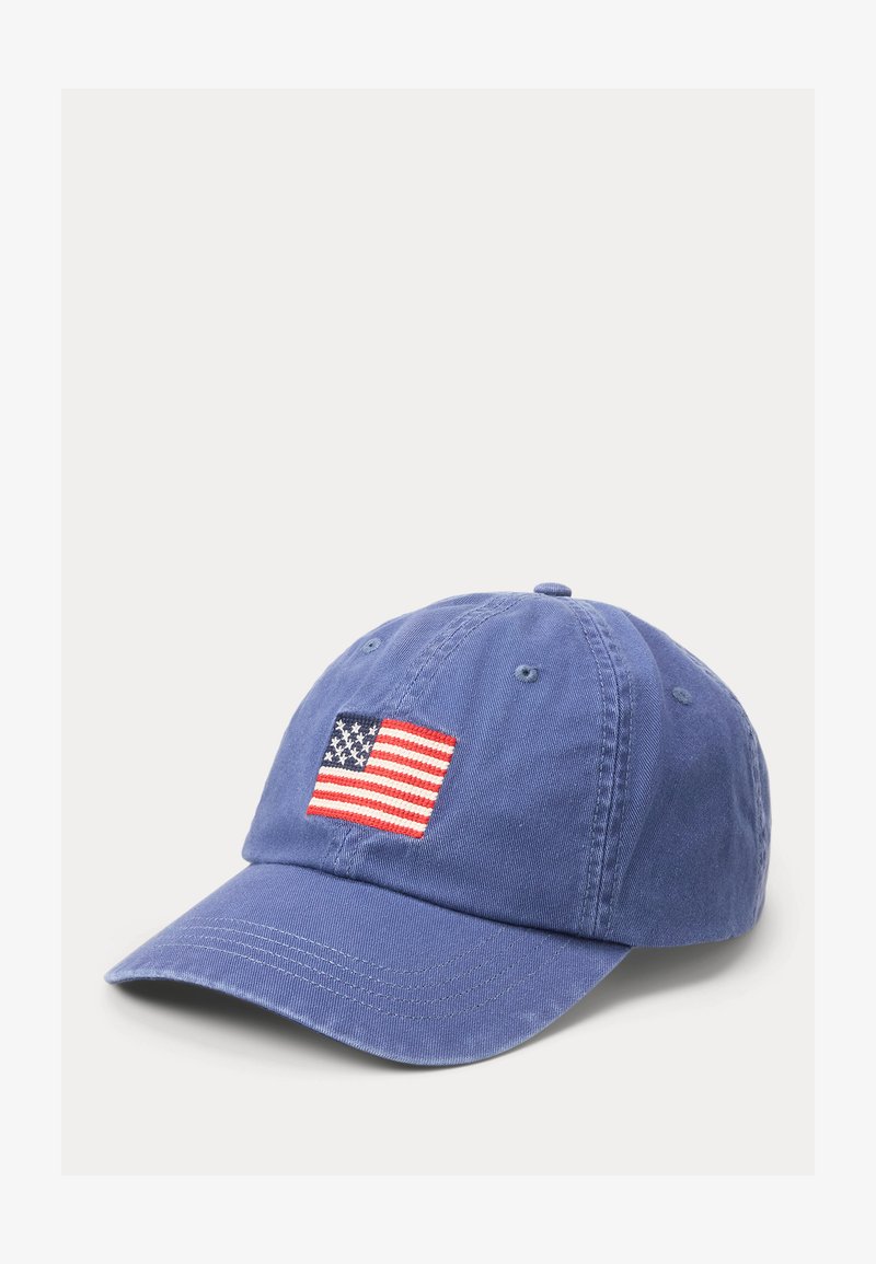 Sinine pesapallimüts tikandiga Ameerika Ühendriikide lipu plaastriga ees, esitatud ühevärvi valgel taustal.