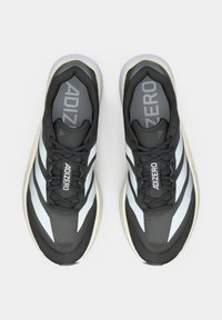Paire de chaussures de course Adidas Adizero noires et blanches vues de dessus sur un fond clair uni.