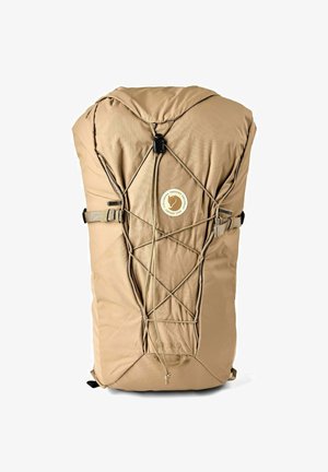 Beige hiking backpack with front bungee cord system, adjustable side straps, and circular brand logo on top center.