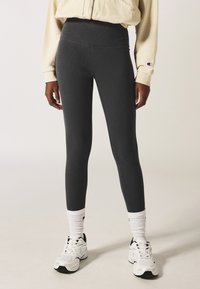 Grijze high-waisted legging gemaakt van ribbelstof, met een gladde textuur, gecombineerd met witte crew-sokken en sneakers.