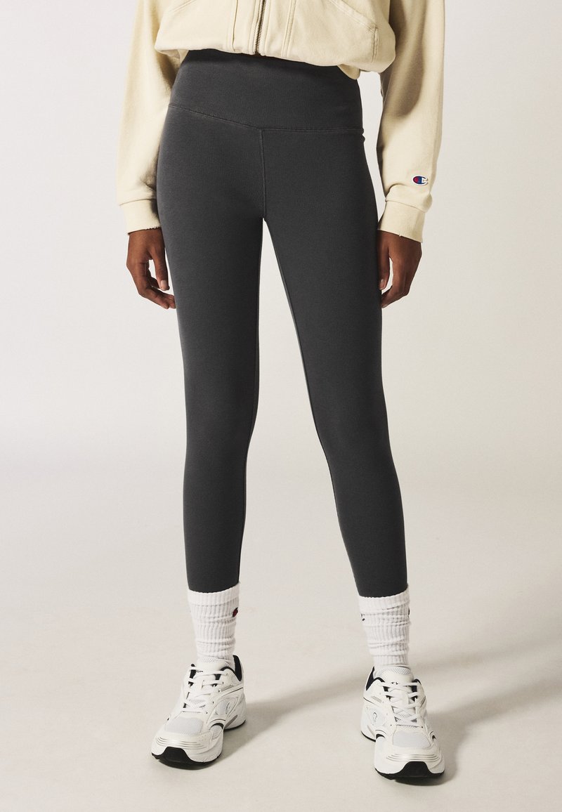 Grijze high-waisted legging gemaakt van ribbelstof, met een gladde textuur, gecombineerd met witte crew-sokken en sneakers.