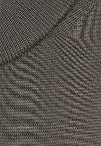 Dzianinowy sweter w ciemnym kolorze taupe, z prążkowanym dekoltem i gładką fakturą, o ściśle utkanych oczkach i minimalistycznych zdobieniach.