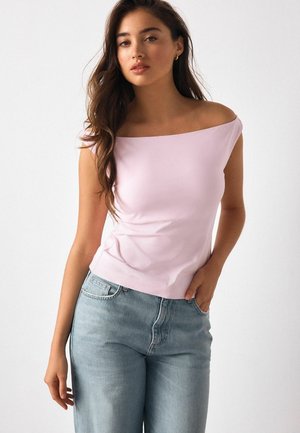 Hellrosa schulterfreies Oberteil aus weichem Stoff, kombiniert mit hellblauen hoch taillierten Jeans aus Denim. Schlichtes Design, glatte Textur.