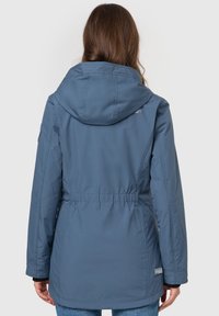 Blå isoleret jakke med snoretræk i taljen, hætte og elastiske manchetter. Har et logo på ryggen. Glat stoftekstur.