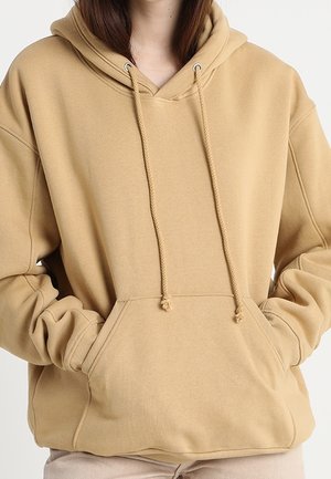 Sweat à capuche beige avec une poche kangourou à l'avant, un cordon de serrage pour la capuche et des poignets côtelés. Tissu doux avec une texture lisse. Design à coupe ample.