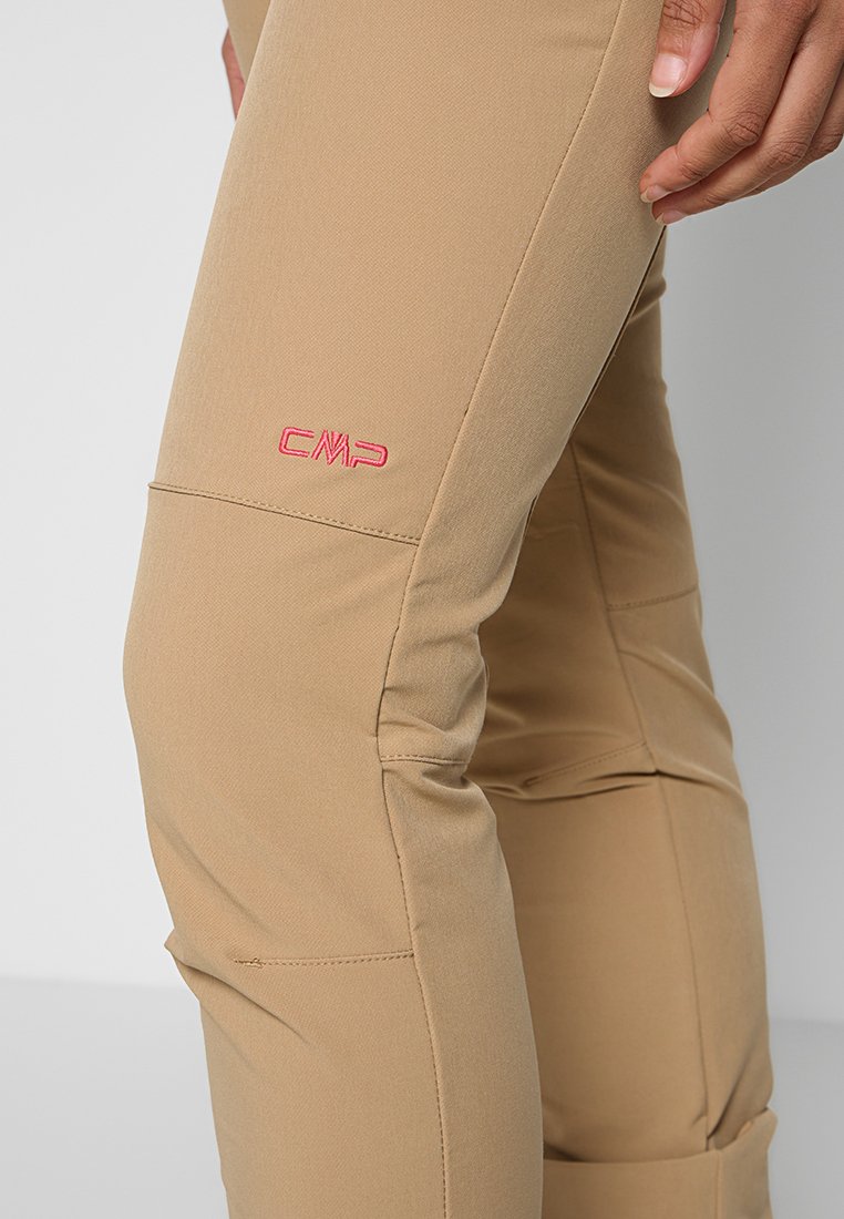Jasnobrązowe spodnie outdoorowe o gładkiej fakturze, z panelami na kolanach i małym różowym logo "CMP" z boku. Posiadają dopasowany krój.