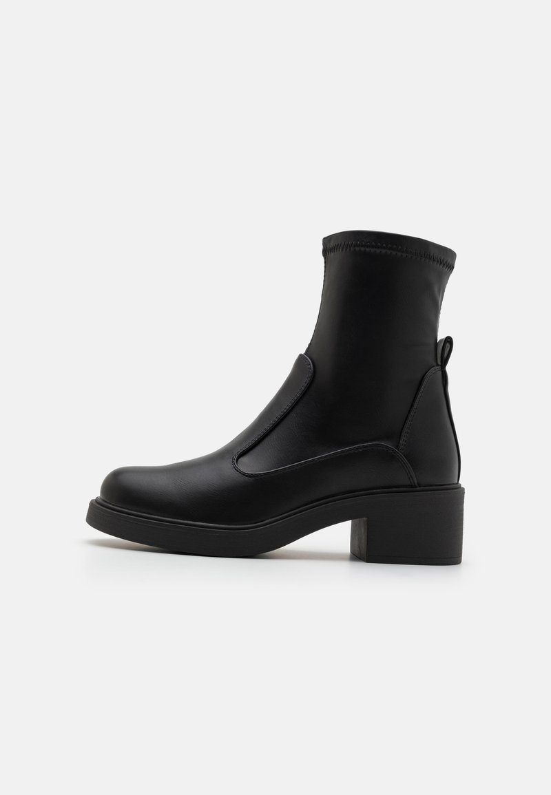 Botas de tobillo negras hechas de cuero suave, con un tacón cuadrado, paneles laterales elásticos y una lengüeta en la parte posterior. Diseño de punta redondeada.
