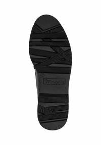 Black rubber shoe sole features a textured pattern with crisscrossed lines, marking, and size label "37" underneath the brand "Tamaris."